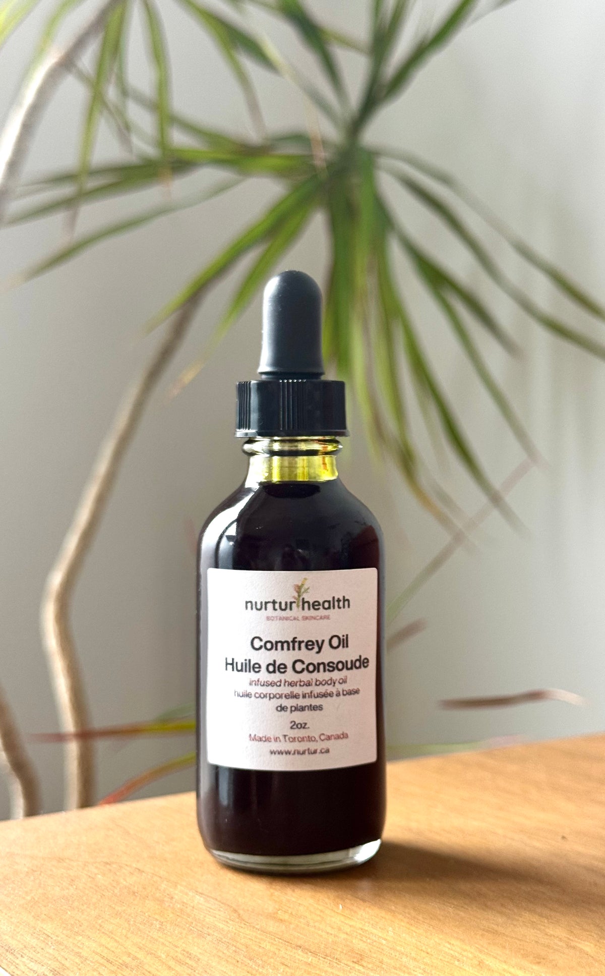 Amber bottle of dark green comfrey infused oil