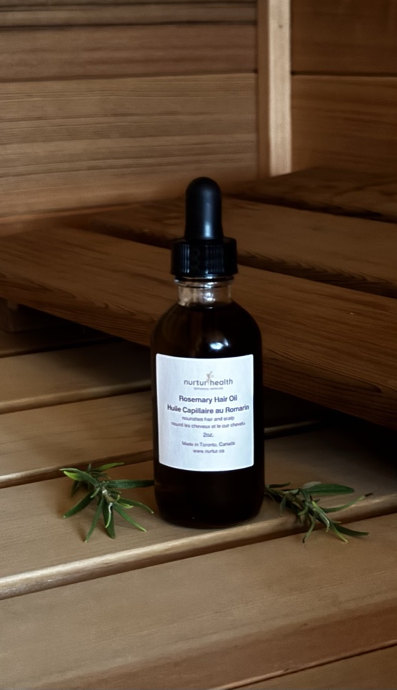 Rosemary Hair Oil on cedar steps with sprigs of rosemary