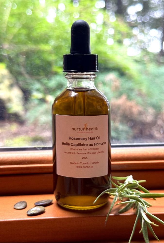 Rosemary Hair Oil on a windowsill with greenery beyond